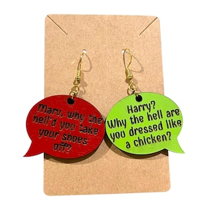 Puede incluir: Un par de pendientes originales. Uno es rojo y tiene forma de bocadillo con el texto "Marv, why the hell'd you take your shoes off?". El otro es verde con el texto "Harry? Why the hell are you dressed like a chicken?"