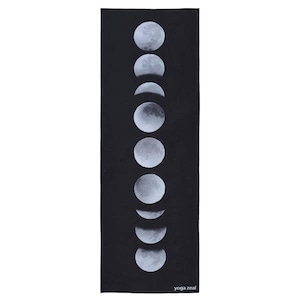 May include: Black yoga mat with a white design of the phases of the moon. The text "yoga zeal" is printed in white at the bottom of the mat.