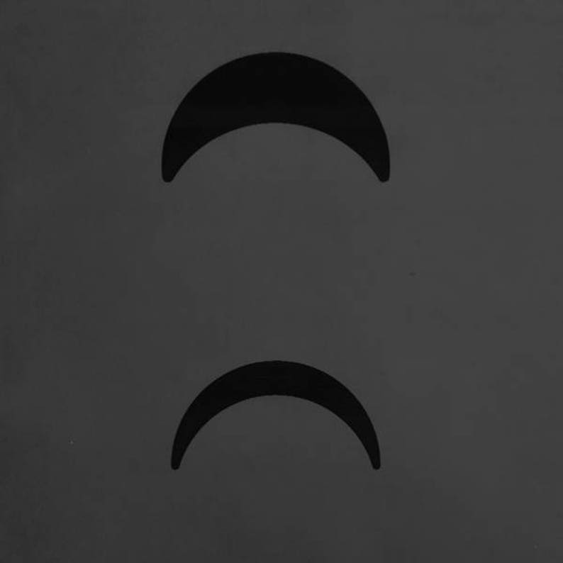 May include: Two black crescent moon shapes on a grey background.