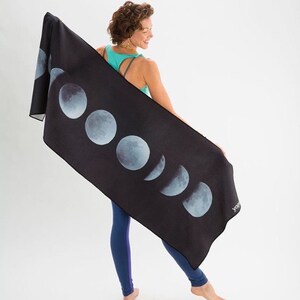 May include: A black yoga mat with a moon phase design. The mat has a white "yoga" logo in the bottom right corner.