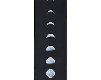 Peut inclure: Tapis de yoga noir avec un motif blanc représentant les phases de la lune. Les phases lunaires sont disposées verticalement, montrant la progression de la lune. Le texte "yoga zeal" est imprimé en bas.