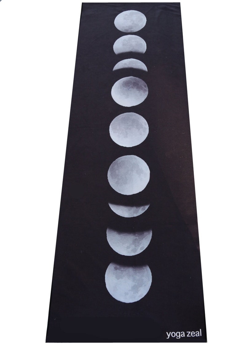 May include: Black yoga mat with a white moon phases design. The mat has the text "yoga zeal" printed on the bottom.