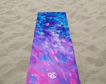 May include: A yoga mat with a colourful abstract design featuring shades of blue, pink, and purple. The mat has a white logo in the centre.