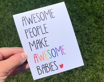 Może przedstawiać: Biała prostokątna kartka okolicznościowa z czarnym napisem AWESOME PEOPLE MAKE, po którym następuje słowo AWESOME w kolorach tęczy oraz słowo BABIES w czarnym kolorze z małym czerwonym symbolem serca na końcu linii.
