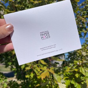 Może przedstawiać: Biała prostokątna kartka okolicznościowa z czarnym napisem PERSONAL PAPER HUGS i r&oacute;żową ikoną serca, po kt&oacute;rej następuje tekst designed & printed in USA &copy; Personal Paper Hugs oraz adres strony internetowej www.personalpaperhugs.com.
