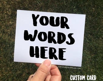 May include: A white card with black text that reads "YOUR WORDS HERE". The card is being held by a hand. The text "CUSTOM CARD" is printed at the bottom of the card.