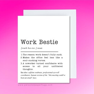 May include: A white greeting card with the text "Work Bestie" in a black, sans-serif font. The card defines "Work Bestie" as a noun, listing reasons why work doesn't fully suck. The card is on a pink background.