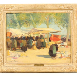 May include: A framed oil painting depicting a bustling outdoor market scene. The painting features a group of people in traditional clothing, shopping at stalls under a canopy of trees. The artist's signature, "Anna Rosen", is visible in the lower left corner, and the painting is titled "Marché de la Place" in the lower right corner.