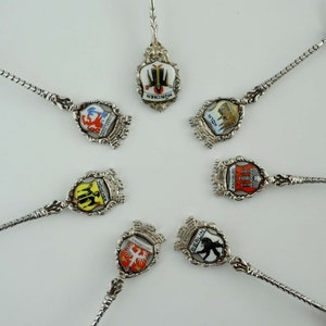 Puede incluir: Conjunto de seis cucharas de plata con escudos de armas de ciudades esmaltados. Los escudos representan las ciudades de Múnich, Colonia, Hamburgo, Fráncfort, Berlín y Mannheim.