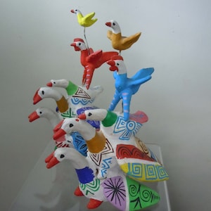 May include: A colorful ceramic sculpture of a group of birds. The birds are stacked on top of each other, with the largest bird at the bottom and the smallest bird at the top. The birds are painted in various colors, including red, blue, yellow, and green.
