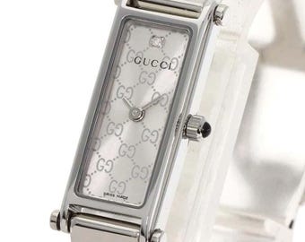 Reloj GUCCI 1500L plateado con esfera GG y diamantes, movimiento de cuarzo suizo para mujer, con caja.