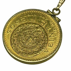 May include: A gold pendant featuring a coin with an intricate Aztec calendar design. The coin is inscribed with the words "VEINTE PESOS ORO PURO" and has a loop for a chain.