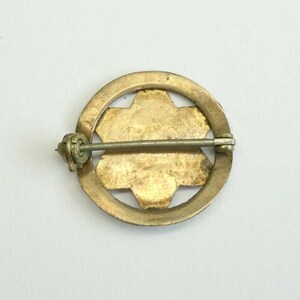 K&ouml;nnte beinhalten: R&uuml;ckansicht einer goldfarbenen Anstecknadel mit einem Sternburst-Design. Die Nadel hat einen Sicherheitsverschluss.