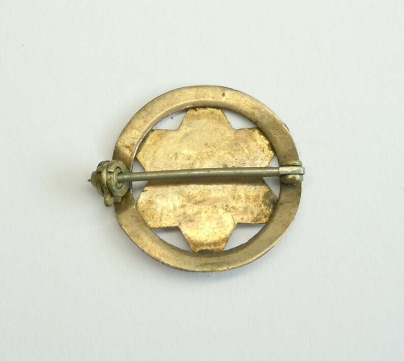 K&ouml;nnte beinhalten: R&uuml;ckansicht einer goldfarbenen Anstecknadel mit einem Sternburst-Design. Die Nadel hat einen Sicherheitsverschluss.