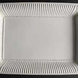 May include: White rectangular serving tray with a raised, beaded rim and a decorative, embossed leaf design at each corner.
