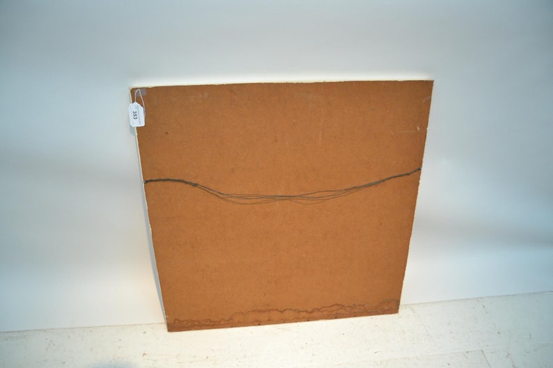 May include: The reverse side of a framed picture, featuring a brown wooden panel with a hanging wire. A small white tag with the number "333" is attached to the upper left corner. The artwork is set against a white backdrop.