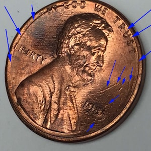 Może przedstawiać: Miedziana moneta amerykańska o wartości jednego centa z napisem "In God We Trust" i "Liberty" umieszczonym wokół krawędzi. Rok "1985" widoczny jest u dołu monety.