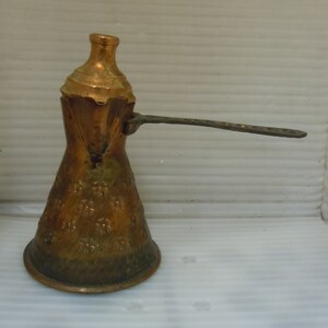 May include: A vintage copper coffee pot with a floral design and a long handle. The pot has a traditional design and is made of a durable metal.