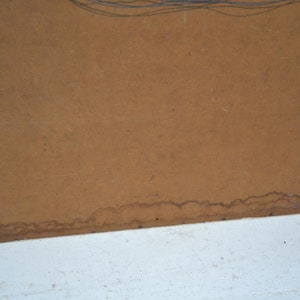 May include: A section of brown paper with a white edge. The paper has a textured surface and some dark brown stains along the bottom edge. Faint blue lines are visible at the top.
