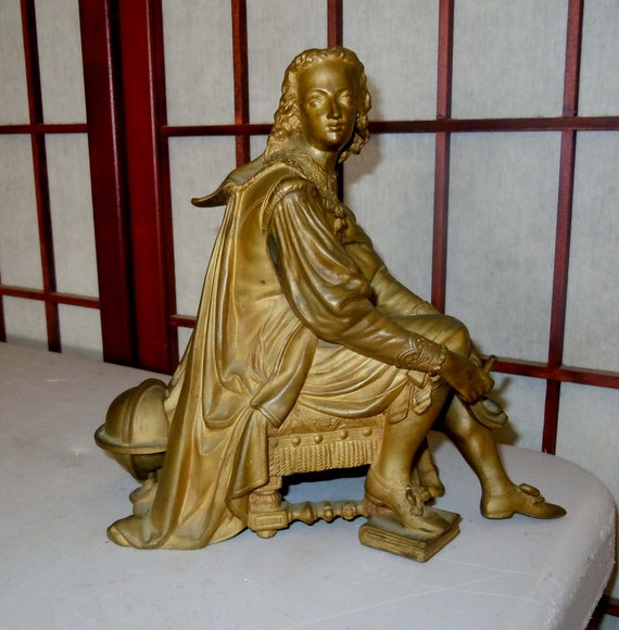 19th early 20th century French gilt bronze depicting a young Christopher Columbus seated on a renaissance style cushion standing upon a book
