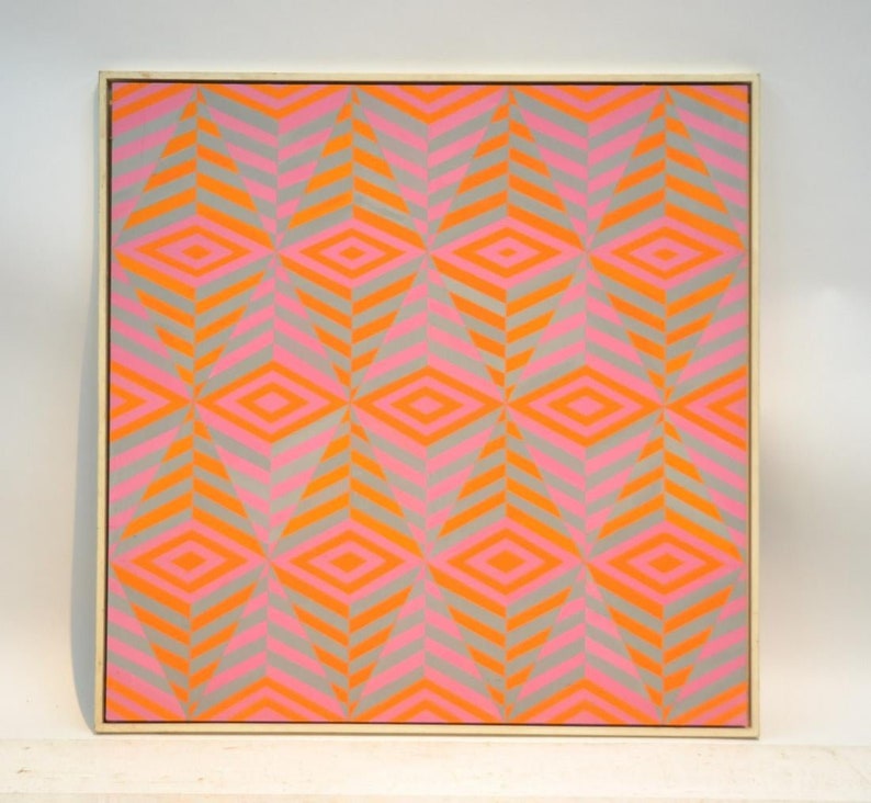 May include: Abstract geometric artwork featuring a repeating pattern of diamonds and chevrons in grey, pink, and orange. The painting is presented in a light-coloured wooden frame.