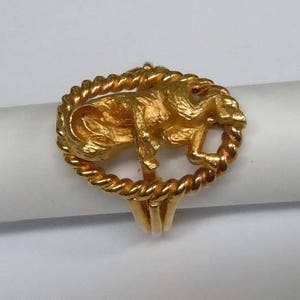 May include: A gold ring with a detailed design of a ram's head in a rope-like circle.