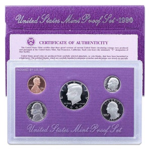 Könnte beinhalten: Ein violettes United States Mint Proof Set aus dem Jahr 1990. Das Set enthält ein Echtheitszertifikat und fünf Proof-Münzen: einen Kupfer-Penny, eine Silber-Halbdollar, eine Silber-Viertel-Dollar, eine Silber-Dime und eine Silber-Nickel. Die Münzen werden in einem durchsichtigen Plastik-Etui präsentiert.