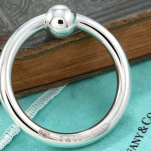 May include: A silver baby rattle with a round ball on the end. The rattle is engraved with "Tiffany & Co."