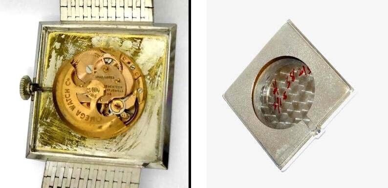 May include: A silver square watch with a silver metal band. The back of the watch is open, revealing the gold-colored inner workings of the watch. The watch is on a white background.