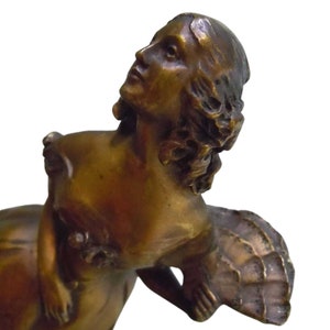 May include: A bronze sculpture of a woman with a fan. The woman is wearing a flowing gown and has her head tilted back. The sculpture is in a vintage style.