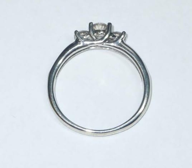 May include: A silver ring with three clear stones set in a prong setting.
