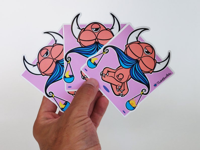 Peut inclure: Trois autocollants de dessin anim&eacute; rose et bleu repr&eacute;sentant un monstre avec des cornes et une barbe bleue tenant une balance avec une lune croissante et un soleil. Les autocollants sont sur un fond rose et portent le texte "PinkySmilers" dans le coin inf&eacute;rieur droit.