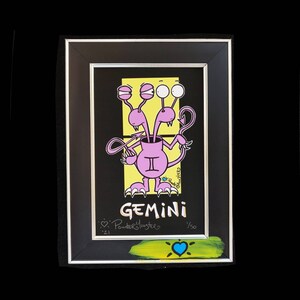 May include: A framed illustration of a pink monster with three eyes and a yellow background. The monster is labeled "Gemini" and signed "Powder Monsters." The artwork is numbered "1/50."
