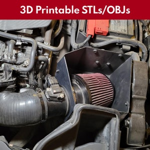 May include: A close-up of a black 3D printed air intake system for a car engine. The intake features a red air filter and a black hose. The system is designed to improve airflow and performance.