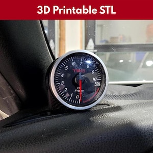May include: A silver and black 3D printed gauge with a red needle and the text "TRD" and "Preis" on the face. The gauge is mounted in a black carbon fiber dashboard mount.