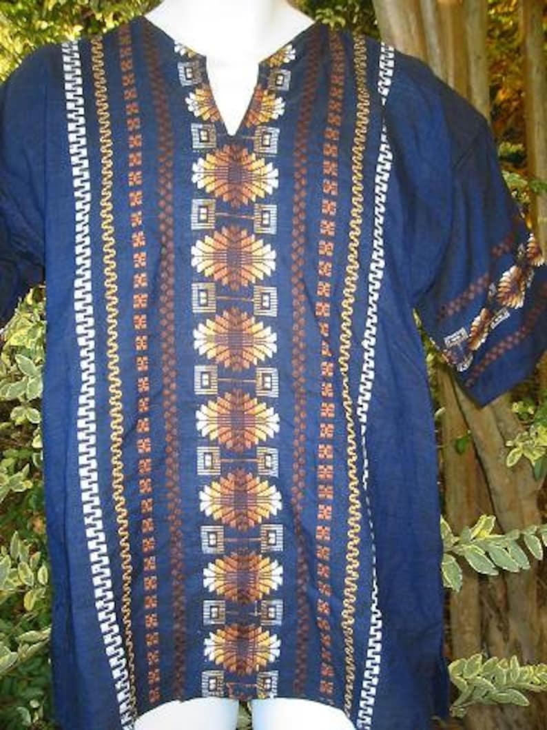 May include: A dark blue tunic with a geometric pattern in shades of brown, white, and yellow. The tunic has a V-neck and short sleeves.