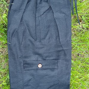 May include: Black cotton shorts with a single button pocket and drawstring waist.