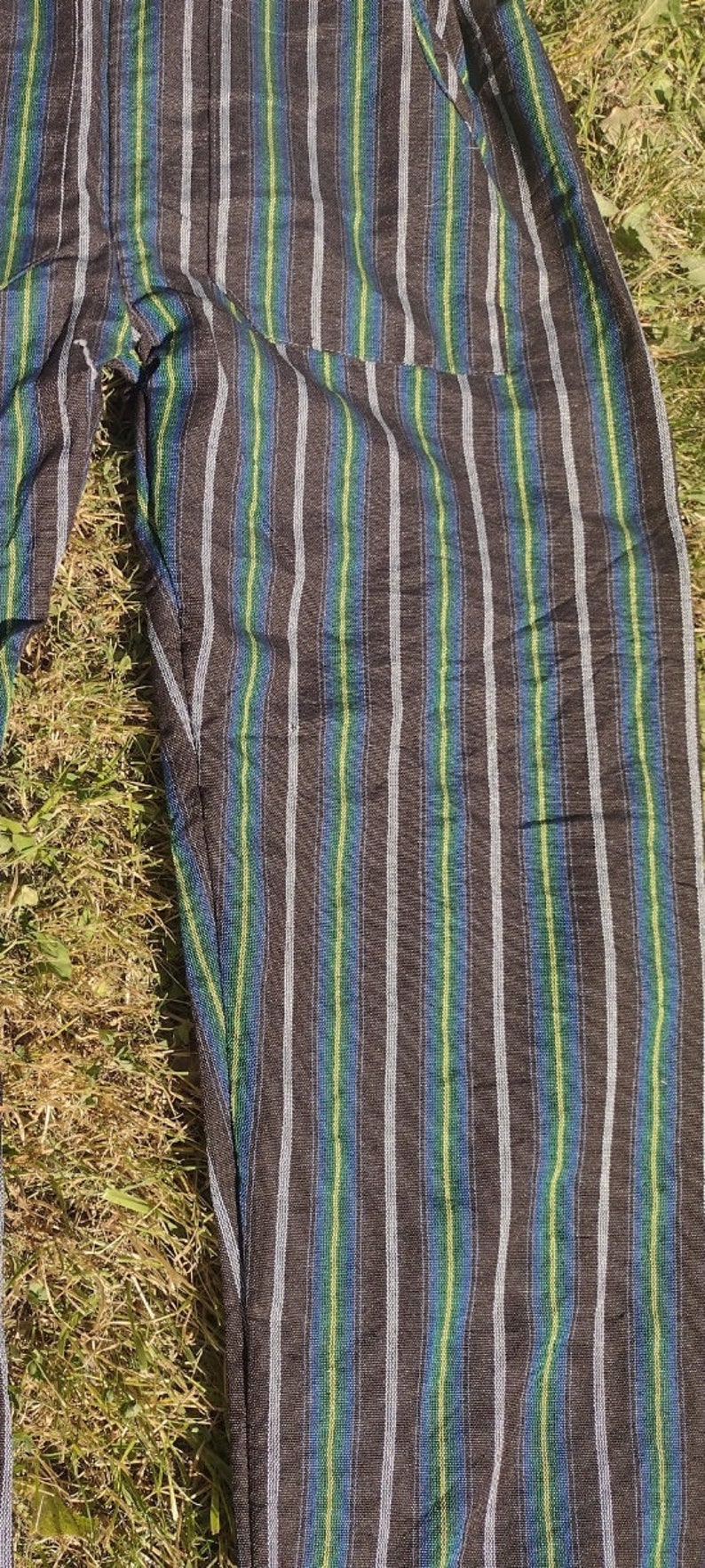 Puede incluir: Pantal&oacute;n negro a rayas con finas rayas blancas, verdes y azules. El pantal&oacute;n tiene un bolsillo en el lado derecho.