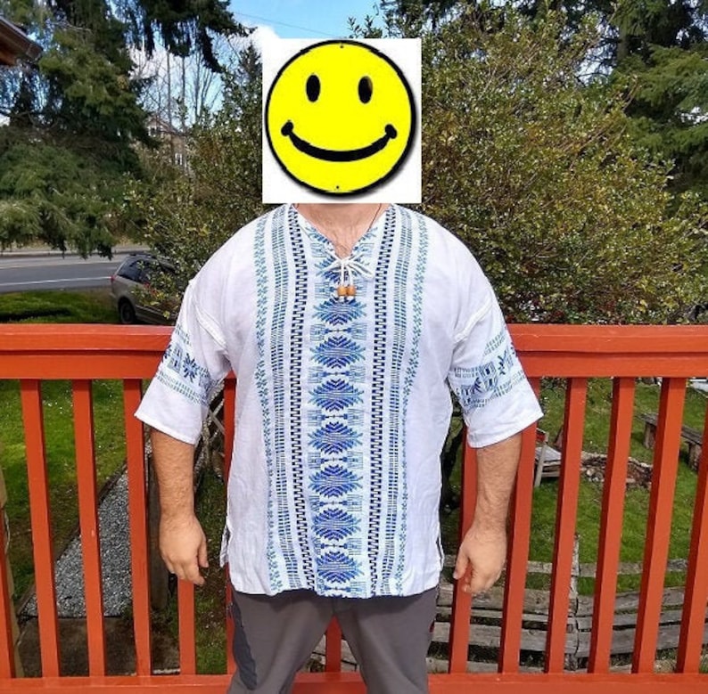 May include: A white shirt with blue and black geometric patterns. The shirt has a V-neck and short sleeves.