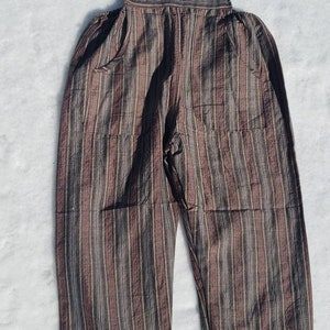 Puede incluir: Pantal&oacute;n vaquero de rayas marrones y negras de algod&oacute;n con tirantes ajustables y bolsillos.