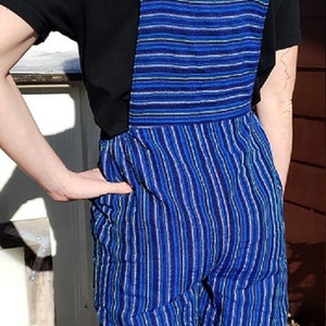 Puede incluir: Pantal&oacute;n vaquero azul y blanco a rayas con una camiseta negra debajo.