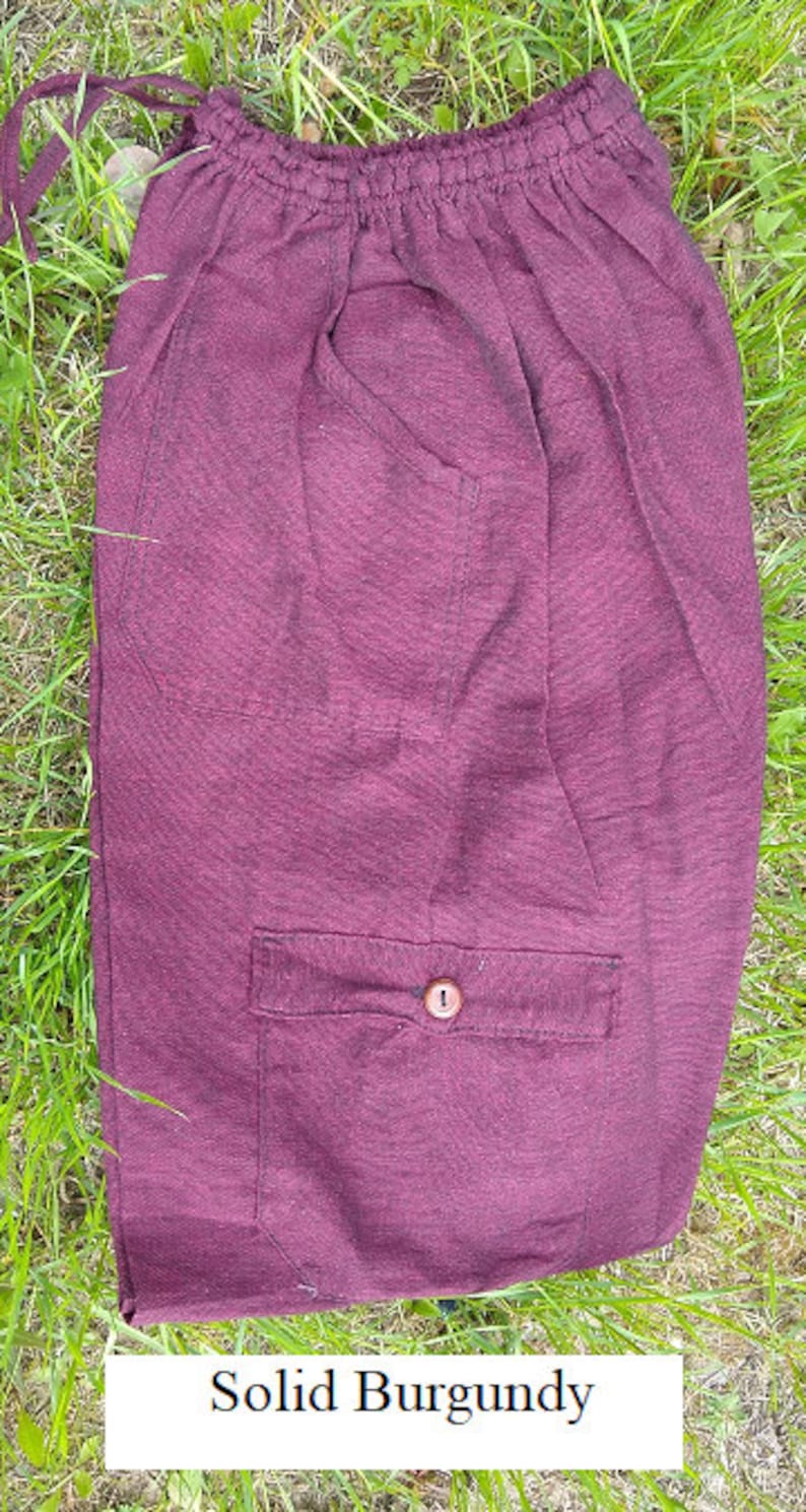 May include: A solid burgundy pair of pants with a drawstring waist and a single button pocket on the front.
