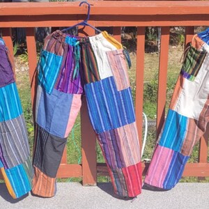 May include: Three pairs of colorful patchwork pants with a drawstring waist. The pants are made of different fabrics and colors, including blue, red, green, purple, and white.