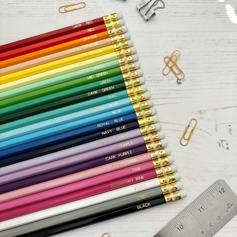 May include: A set of 20 colored pencils with gold-toned metal ferrules and eraser tops. The pencils are arranged in a row from dark red to black, with each pencil labeled with its color name.