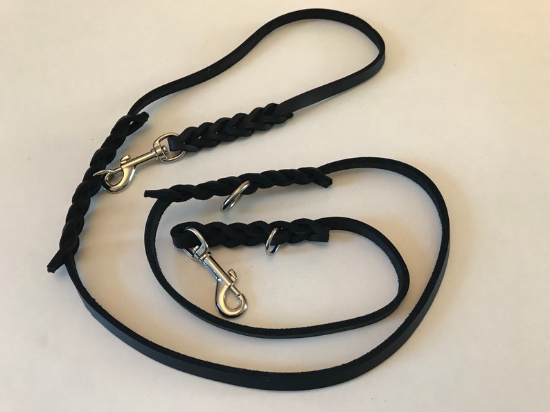 May include: Two black leather dog leashes with silver clips. The leashes are braided and have a flat strap.