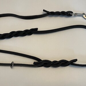 May include: A black leather dog lead with a braided section and a silver clip.