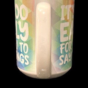May include: White ceramic coffee mug with a colorful geometric pattern and the text "It's easy for you to say" on the right side and "Too busy to worry" on the left side.