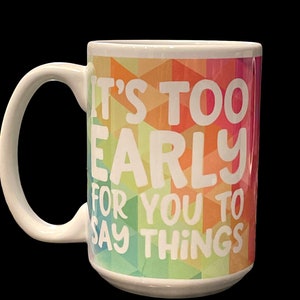 May include: White ceramic coffee mug with a colorful geometric pattern and the text "It's too early for you to say things".