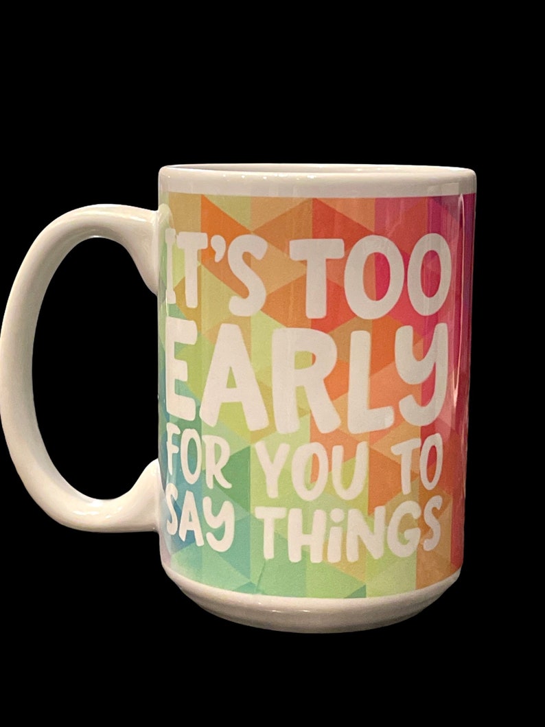 May include: White ceramic coffee mug with a colorful geometric pattern and the text "It's too early for you to say things".