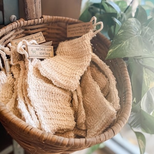 May include: A wicker basket filled with natural sisal soap bags. The bags are made of a soft, textured material and are perfect for exfoliating and cleansing the skin. The label on the bag reads "Natural Sisal Soap Bag".